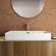Waschtisch von Ideal Standard in Seidenweiß auf Holzunterschrank, rechteckig mit einfachem Wasserhahn, Spiegel darüber, vor korkhaltiger Wand.